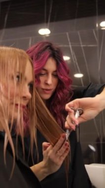 Yetenekli ve profesyonel bir stilist, şık ve şık bir salon ortamında müşterilerinin saçı üzerinde titizlikle çalışıyor..