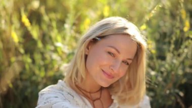 Canlı yeşillik ve yumuşak altın ışıkta gülümseyen bir kadının huzurlu portresi büyülü bir atmosfer yaratıyor..