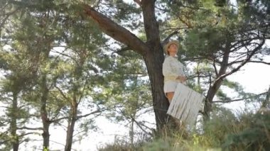 Huzurlu bir anda, bir kadın uzun bir ağacın yanında otururken doğasında nefes kesici bir güzellik bulur.