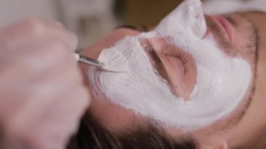 Rahatlatıcı, sakin bir spa ortamında bir adam rahatlatıcı bir yüz bakımı alır..