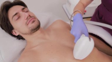 Bir erkek hasta, klinik bir ortamda düşünceli bir şekilde profesyonel bir cilt tedavisi görüyor..