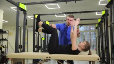 Modern bir spor salonunda, profesyonel bir antrenör pilates egzersiz sırasında bir kadına ustalıkla rehberlik eder.