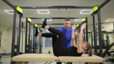 Kişisel antrenör aktif olarak müşterinin karın egzersizleri yapmasına yardımcı oluyor. Spor salonu..