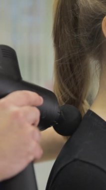Spor salonundaki kadınların boyun kaslarını gevşetmek için ellerinde masaj silahı tutan erkek spor ayakkabıları..