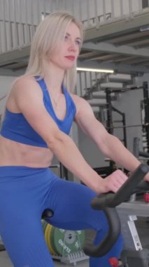 Spor yapan kadın spor bisikleti eğitimi alıyor. Kapalı alanda, yakın plan. Kardiyo çalışması.