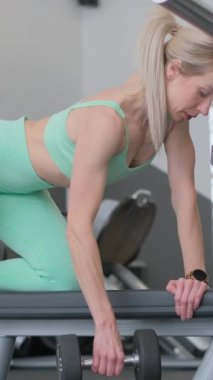 Spor salonunda dambılları kaldıran güzel bir kadın. Spor yaşam tarzı konsepti.