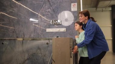 Mutlu anne ve kız musluğu duş için suyla açıyorlar. Banyo yenileme için hijyenik malzeme seçiliyor.