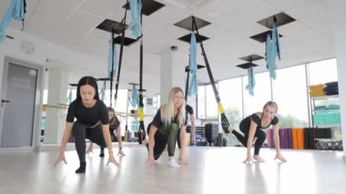 Üç genç kadın TRX döngüsü yapıyor. Spor salonu. Yüksek kalite 4k görüntü