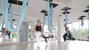 Katılımcılar güzel tasarlanmış çağdaş bir stüdyoda mavi hamaklarla hava yogası uygulaması yaptılar..