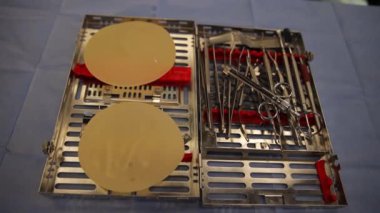 Steril bir tıbbi yüzeye göğüs implantlarıyla birleştirilmiş cerrahi aletler koleksiyonu..
