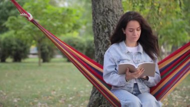 Doğası gereği güzelliklerle çevrili sıcak bir hamakta dinlenirken büyüleyici bir kitap okumanın mutlu ve huzurlu bir anı.