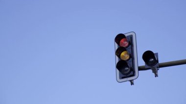 Durma ihtiyacını simgeleyen parlak kırmızı bir trafik ışığı açık mavi gökyüzüne çarpıyor..