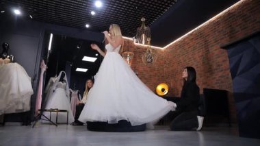 Gelin, göz kamaştırıcı elbisesini profesyonel yardımla şık bir butik atmosferde sergiliyor..