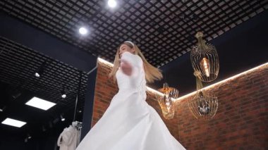 Parlak bir gelin, güzel beyaz bir gelinlik içinde mutluluğunu ve tarzını sergileyerek sevinçle döner..