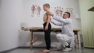 Genç bir çocuk, uzman bir doktorla bir sağlık kliniğinde kapsamlı bir sağlık değerlendirmesi ve muayene görüyor..