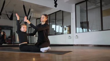 Parlak ve enerjik bir stüdyoda, yetenekli bir yoga eğitmeni, bir çocuğa huzurlu bir şekilde rehberlik ediyor.