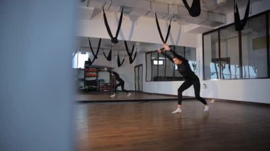 Güzel bir kadın, aynalı geniş bir stüdyoda zarif bir yoga pozu sergiliyor..