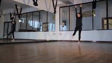 Bir kadın büyük aynalarla dolu bir stüdyoda jimnastik yapıyor..