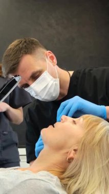 Klinikte yaşlı bir kadın hastayla çalışan dişçi. Dikey video.