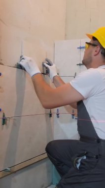 Erkek zanaatkar duvara seramik fayanslar yerleştiriyor, yakın plan. Dikey video.