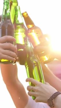 Gün batımında yakın planda bira içen arkadaşlar. Dikey video.