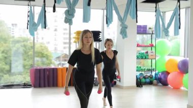 Renkli stüdyodaki bir grup kadın ağırlıklarla dinamik fitness dersi veriyor. Fitness egzersizi.