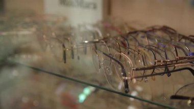 Yakından bakınca, el değmemiş cam bir rafta zarif bir şekilde sergilenen çeşitli gözlükler görülüyor..