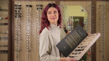 Modern, lüks bir optik butikte müşteriler için modaya uygun gözlük takan zarif bir kadın..