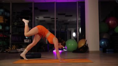 Bir kadın atletizm ve esnekliğini göstermek için tam bir bölünme sergiliyor. Modern bir fitness ortamında.