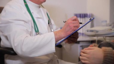 Bir doktor, hastaya sağlık sorunları ve sağlık durumları hakkında danışmanlık yaparken not alır..