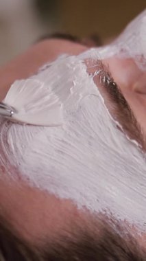 Erkek bir müşteri, erkek sağlığı ve sağlığı için spa tedavilerinin yararlarını vurgulayarak, huzurlu bir spa ortamında, gençleştirici bir yüz terapisi uyguluyor..