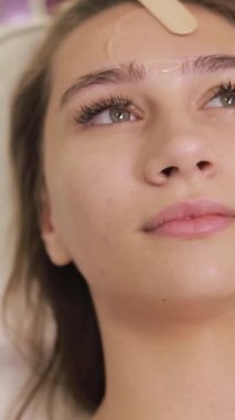 Bir yüz terapisi seansı sırasında rahatlatıcı bir an, canlı sarı bir maskenin uygulanması, rahatlamanın ve cilt tazelenmesinin teşvik edilmesi,.