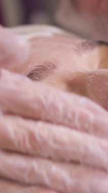 Profesyonel cilt bakımı tekniklerini ve derin rahatlamayı vurgulayan sakin bir yüz tedavisi seansının dikey videosu.