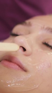 Profesyonel bir estetisyen yüz bakımı sırasında ileri teknoloji cilt bakım ürünleri uygular, istisnai cilt gençleştirme ve müşteri için derin rahatlama sunmaya odaklanır..