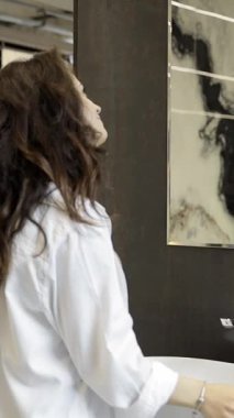 Çağdaş bir mobilya dükkanındaki yuvarlak aynayı inceleyen bir kadın, aynanın banyo dekoru ile bütünleşmesini hayal ediyor..