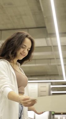 Ev dekorasyonu mağazasında duvar kağıdı seçimlerini inceleyen bir kadının dikey videosu.