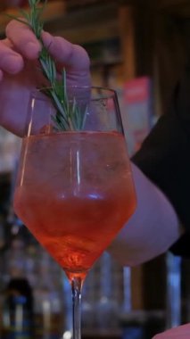 Dikey video yetenekli bir barmen hayat dolu bir barda ferahlatıcı bir içki hazırlıyor..