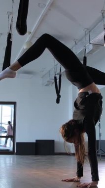 Bir kadın spor salonunda amuda kalkıyor. Dikey video.