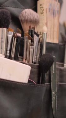 Siyah deri bir düzenleyicide farklı boyutlarda birçok makyaj fırçası var. Dikey video.