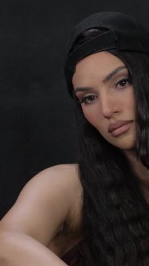 Dalgalı saçları, çıplak omuzları ve altın bir zinciri olan şık bir esmer. Dikey video. 