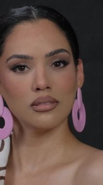 Dalgalı saçları, çıplak omuzları ve boynunda altın bir zincir olan büyüleyici bir esmer profesyonel bir fotoğrafçı için zarif bir poz veriyor. Güzellik ve zarafet sergiliyor. Dikey video.