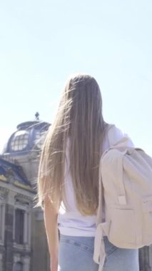 Sırt çantalı meraklı bir gezgin güneşli bir günde nefes kesici bir mimari keşfediyor. Dikey video.