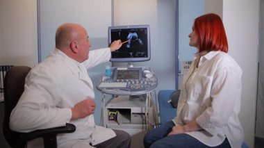 Yetenekli bir doktor hastaya ultrason görüntülerini dikkatlice gösterir. Önemli ayrıntıları vurgular ve açıklar.