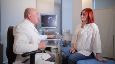 Bir hasta, klinik bir ortamda güvenilir doktoruyla sağlık sorunları hakkında konuşuyor..