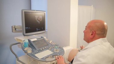 Bir tıp uzmanı klinik ortamda ultrason muayenesi yapar. Dikey video.