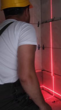 İnşaat işçisi inşaat sürecinde tam olarak yerleştirmek için lazer seviyesinde bir araç kullanır.