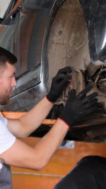 Becerikli bir tamirci, bir aracın gövdesinin altında gerekli bakımı yapar, uzmanlık ve zanaatkarlık sergiler.