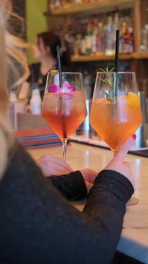 İki canlı ve renkli kokteyl güzel çiçeklerle süslenmiş ve şık bir barda taze meyveler..