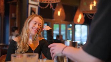 Neşeli bir kadın neşeli ve hayat dolu bir restoran atmosferinde keyifli bir içkinin tadını çıkarırken yürekten güler..