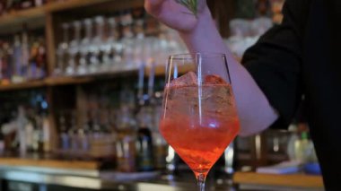 Canlı ve renkli bir kokteyl. Güzelce süslenmiş ve canlı bir bar ortamında servis edilmiş.